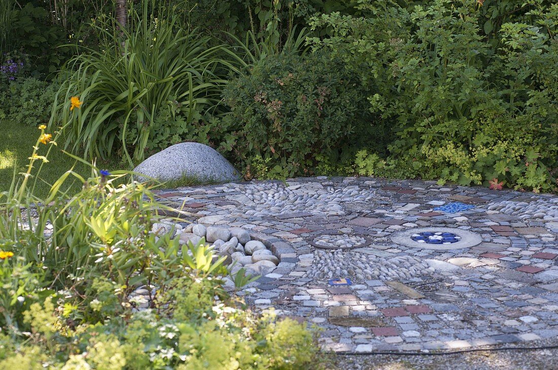 Interestingly paved small terrace between flower beds