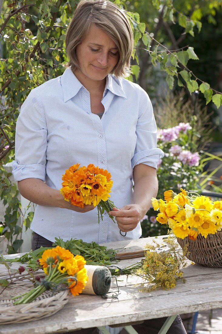 Frau bindet Strauß aus Calendula (Ringelblumen) und Fenchel (Foeniculum)