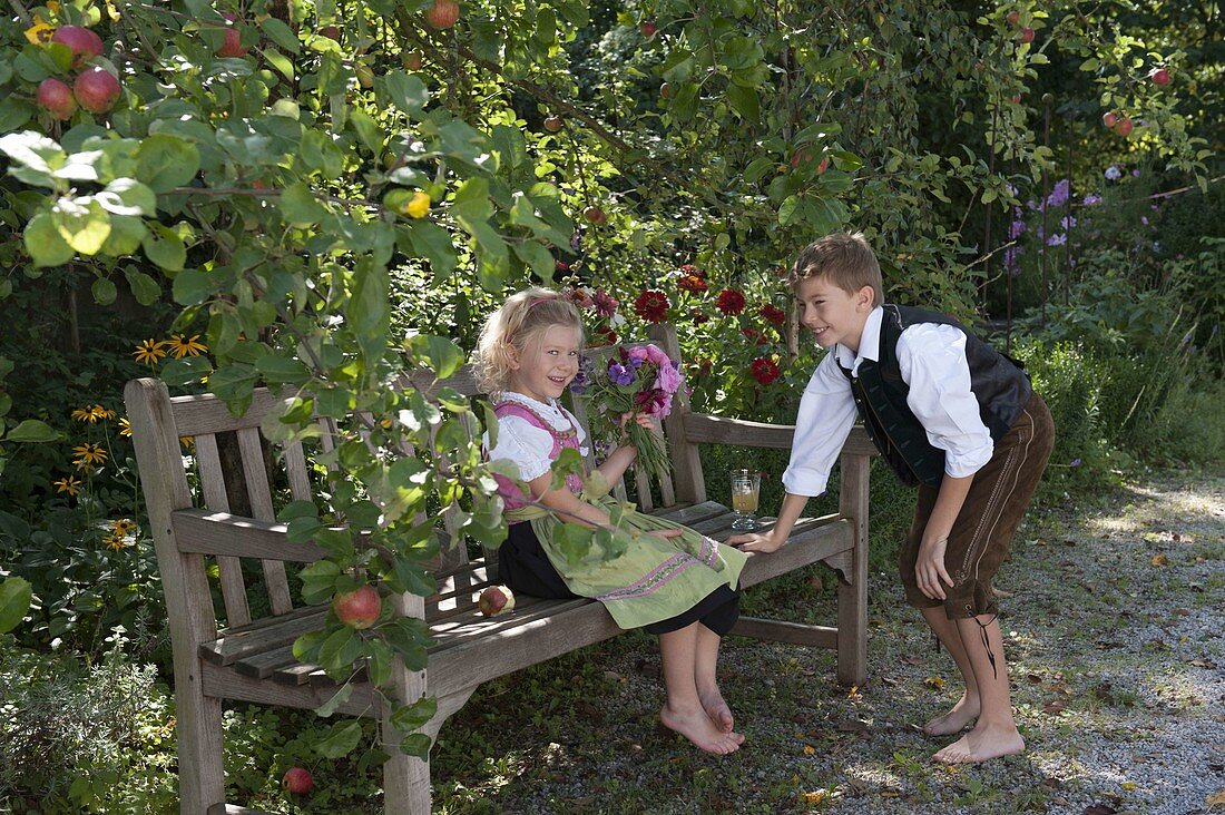 Mädchen im Dirndl mit Duftstrauß aus Rosa (Rosen) und Lathyrus odoratus