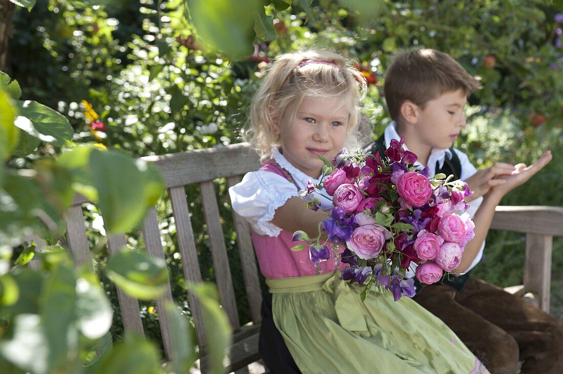 Mädchen im Dirndl mit Duftstrauß aus Rosa (Rosen) und Lathyrus odoratus