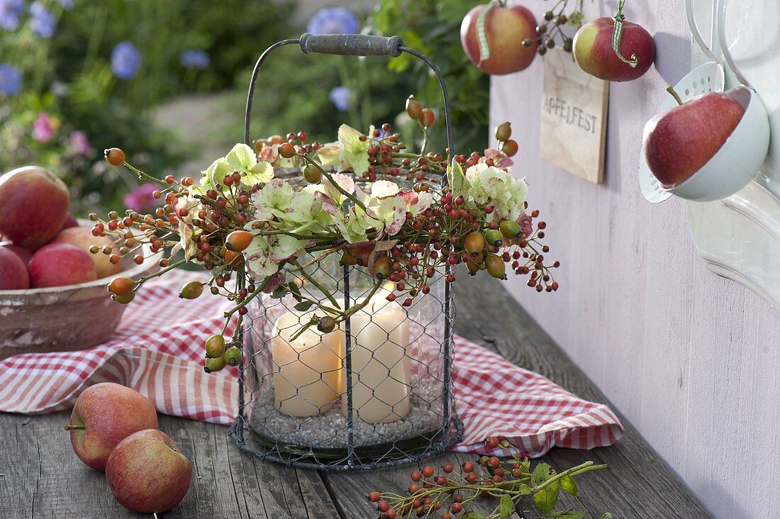 Glas-Windlicht im Drahtkorb mit Kranz aus Hydrangea (Hortensie) und Rosa