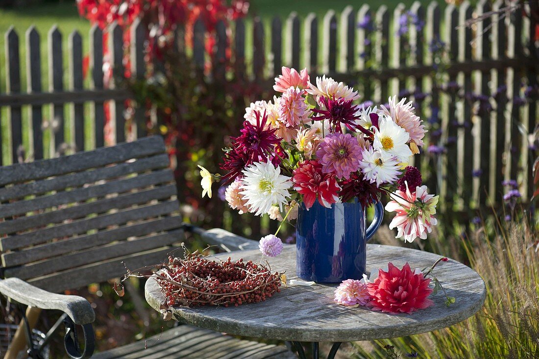 Strauß aus gemischten Dahlia (Dahlien) in blauem Krug und Kranz