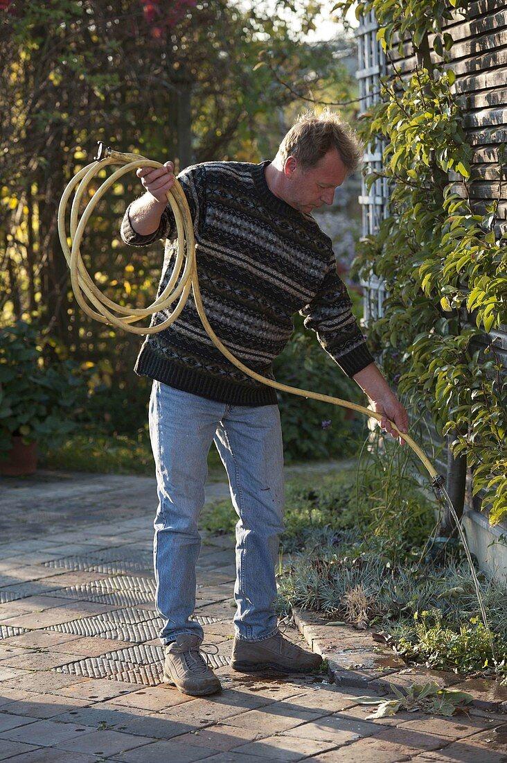 Man emptying garden hose before winter storage