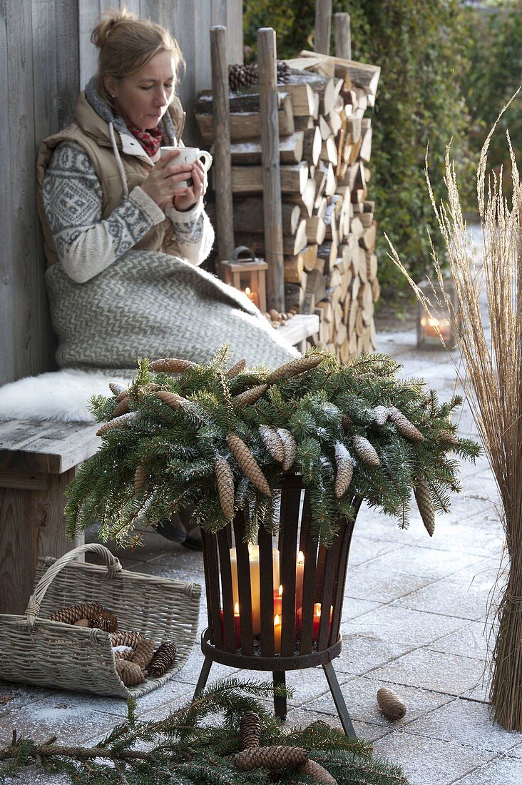 Wreath of Picea omorica (spruce) with cones on a fire basket with candles