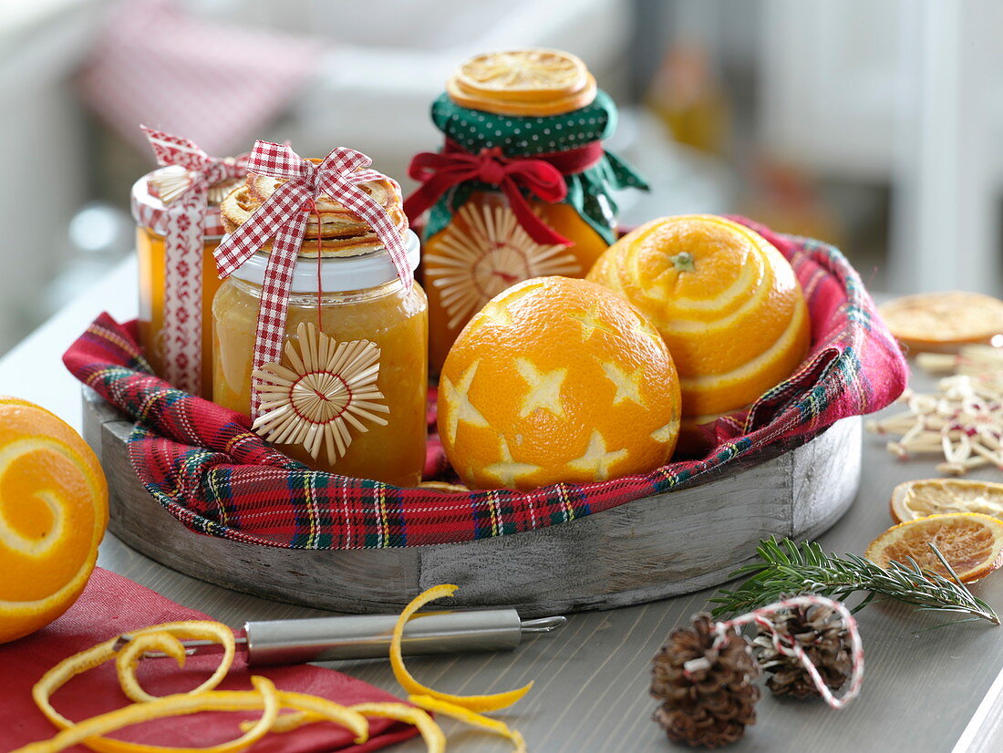 Holztablett mit Apfelsinen (Citrus sinensis), Gläser mit Orangenmarmelade