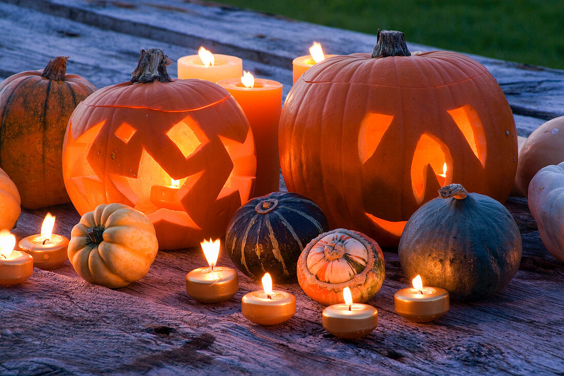 Halloween: Stilleben auf einem nächtlichen Holztisch mit Kerzen, Kürbissen, Kürbissen und Kürbissen