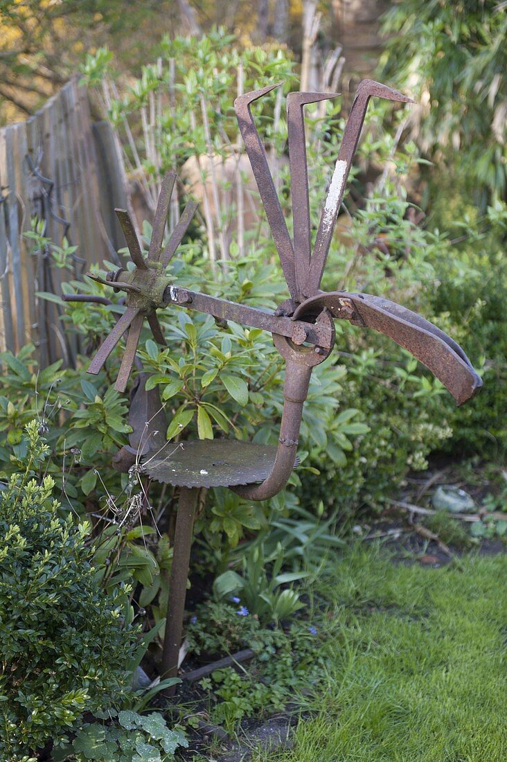 Skulptur aus alten Eisenteilen zusammengebaut im Beet