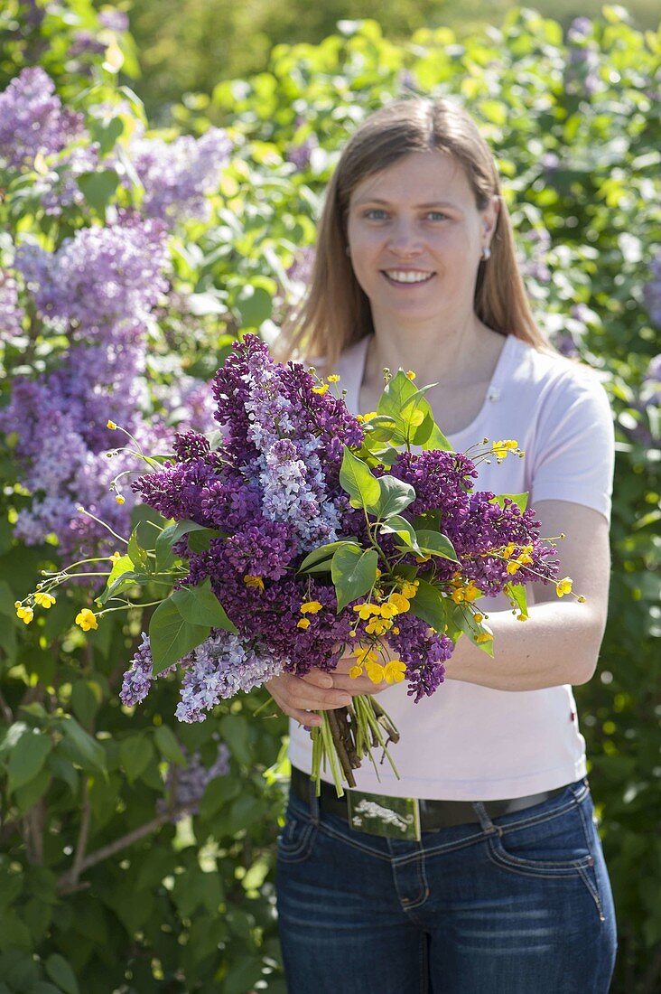 Woman with fragrant bouquet of Syringa (lilac) and Ranunculus acris