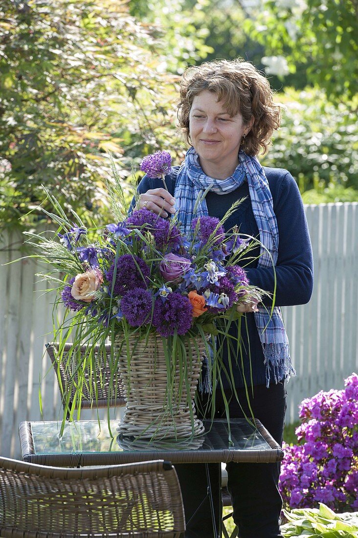 Woman sticks bouquet of Allium 'Globemaster' (ornamental leek), pink (roses)