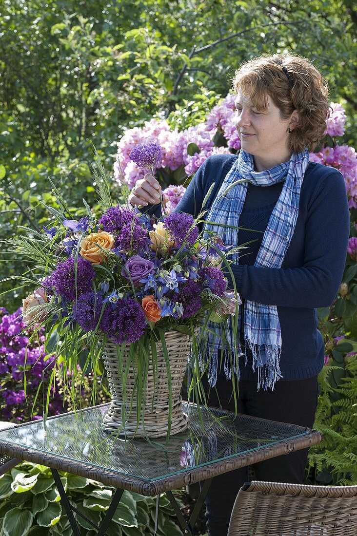 Woman sticks bouquet of Allium 'Globemaster', pink (roses)