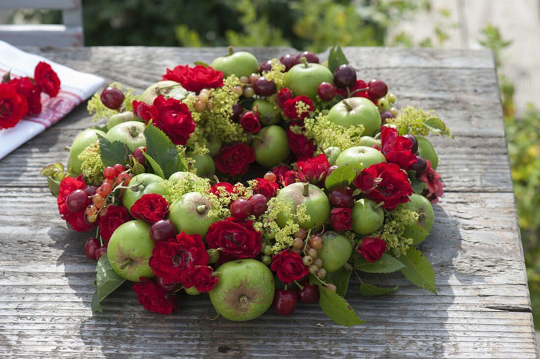 Wreath of pink (roses), fallen green apples (Malus)