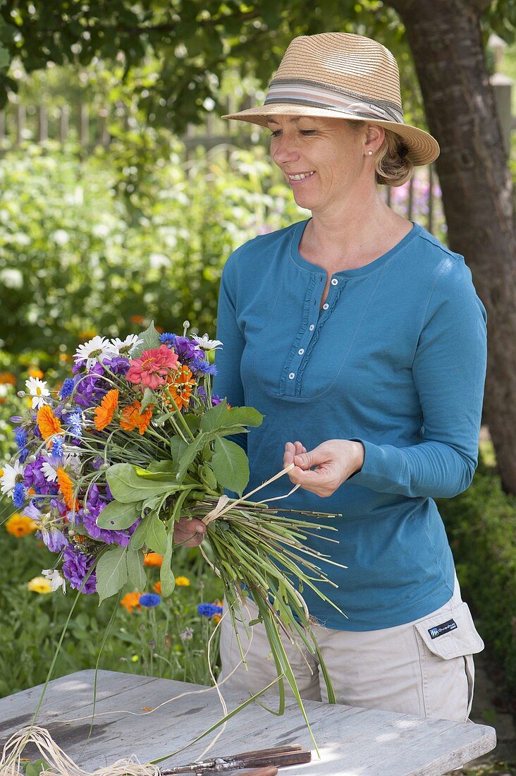 Woman tying a colourful bouquet of summer flowers