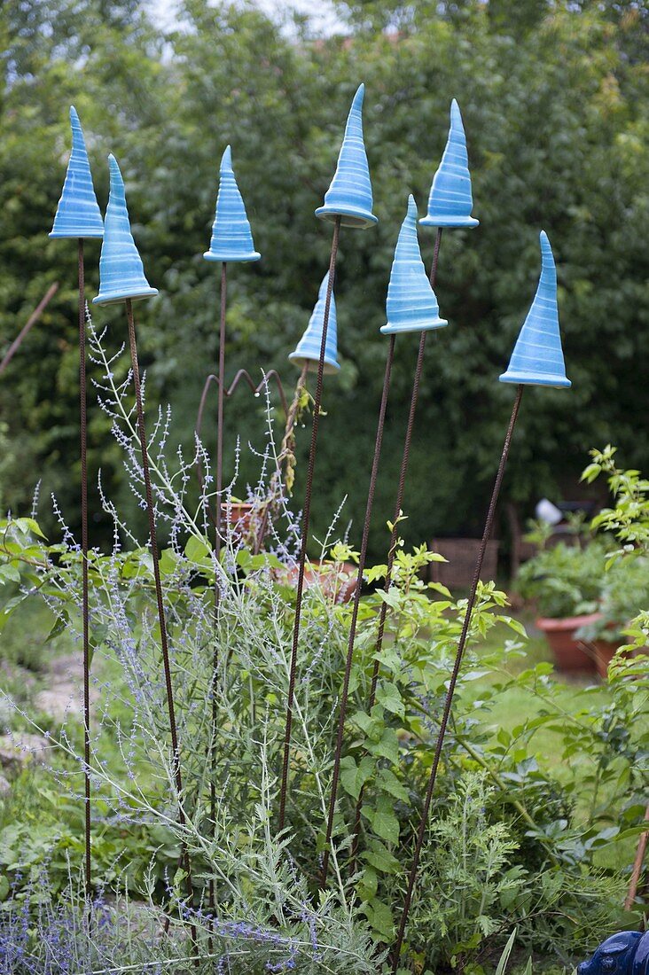 Potted pointed hats on iron rods in the bed as garden plugs