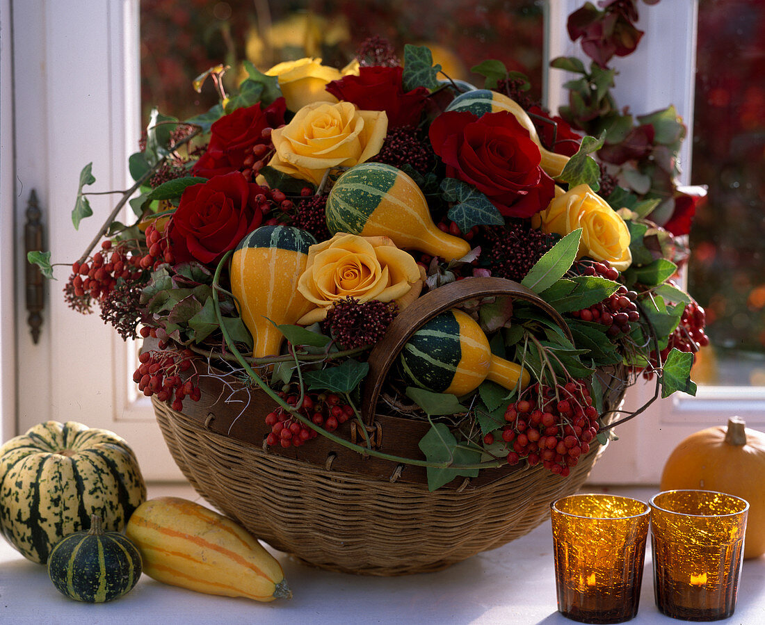Basket with autumn arrangements of roses, ornamental pumpkins and berry decorations