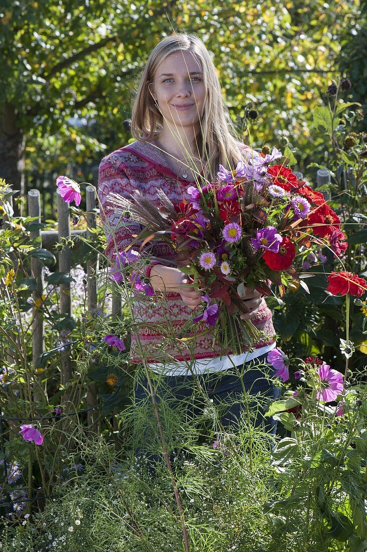 Junge Frau schneidet die letzten Sommerblumen im Bauerngarten