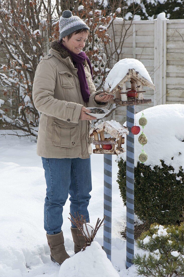 Woman filling bird feeders on curled wooden pegs