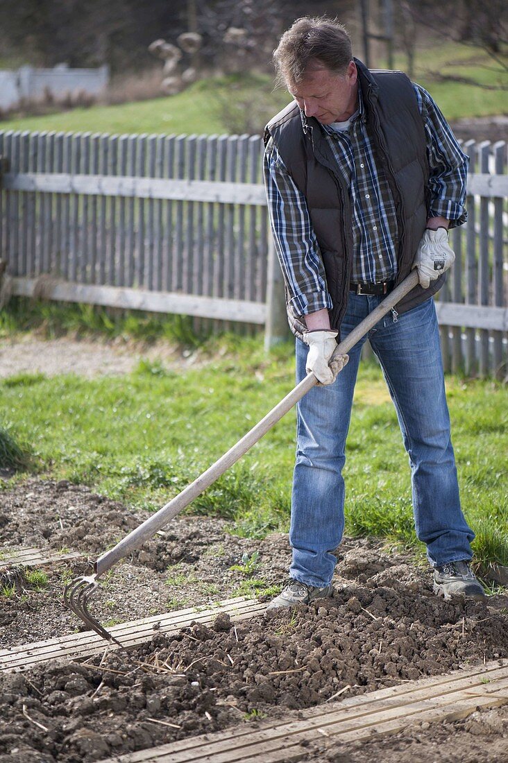 Man loosening the soil with a wedge