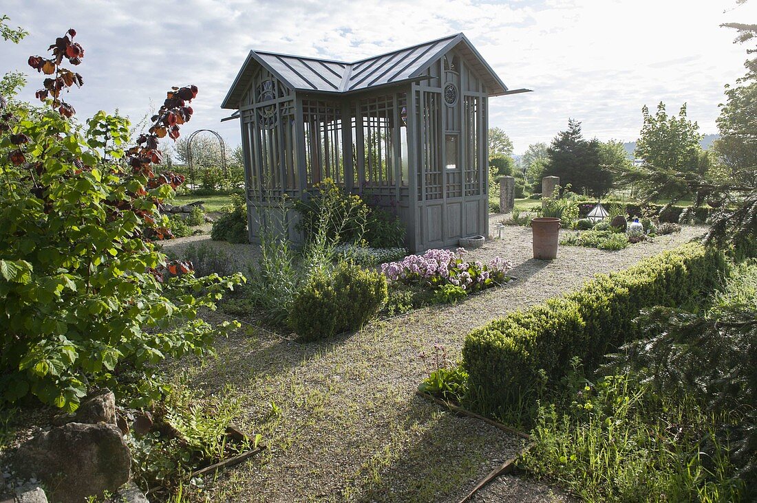 Gartenhaus mit Stauden- und Kräuterbeeten, Kieswege, Hecke aus Buxus