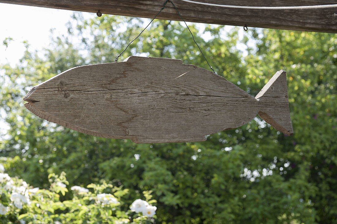 Aus altem Bauholz ausgesägter Fisch als Dekoration aufgehängt