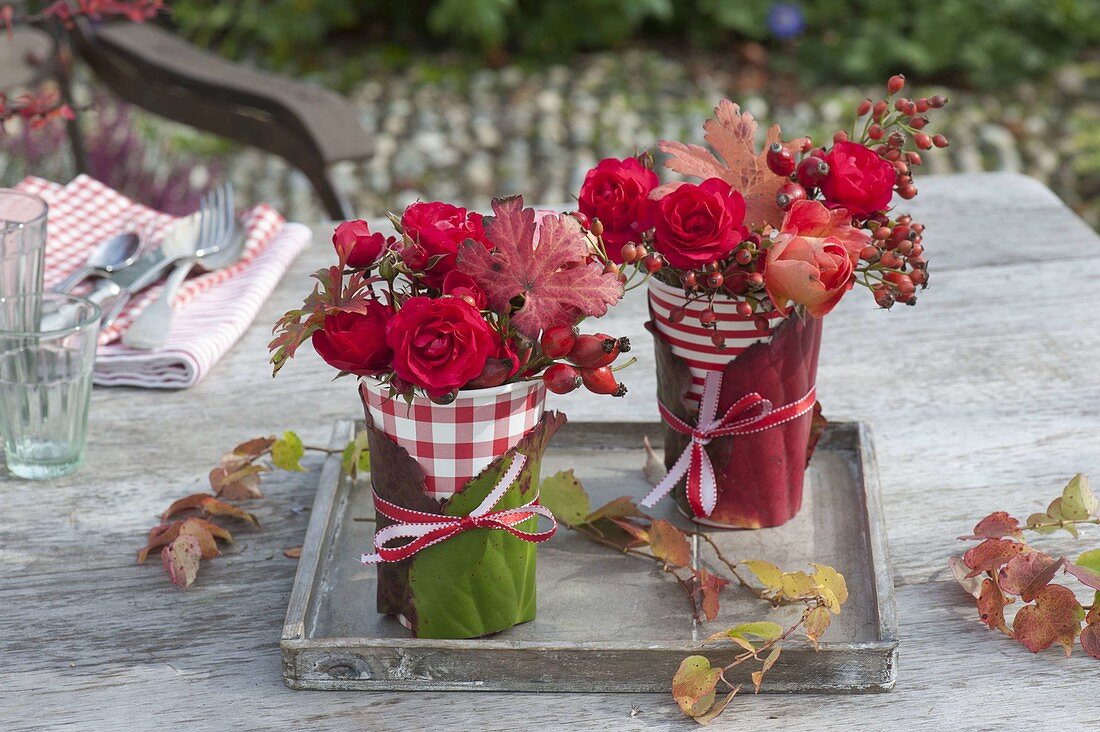 Red and white drinking cups as vases with bergenia leaves
