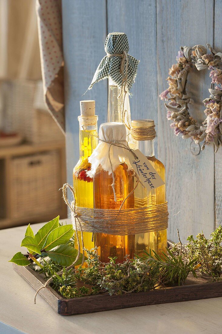 Bottles with herb vinegar and oil tied together on wooden coaster