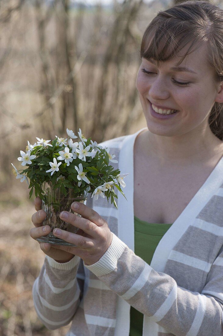 Woman with a little Anemone nemorosa (Wood anemone) bouquet