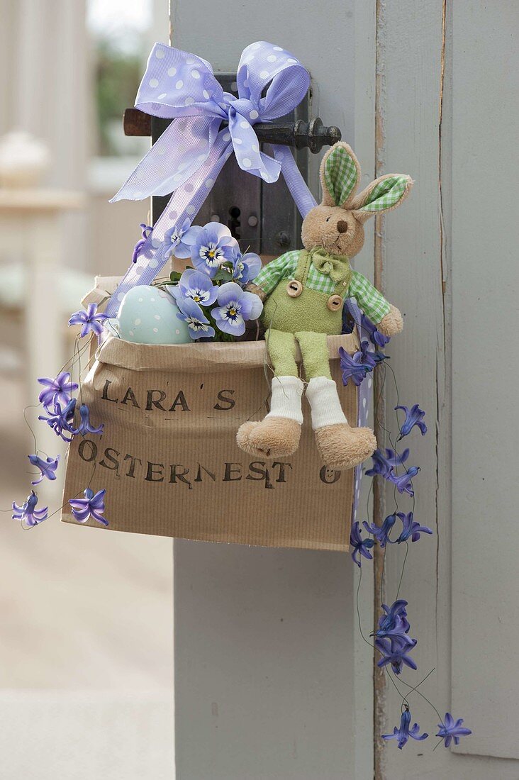 Printed paper bag Lara's Easter basket with purple bow hung on door handle