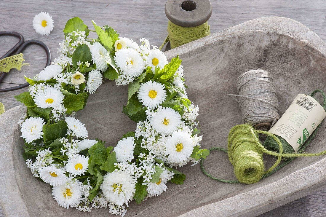 Tying a wreath of daisies and herbs