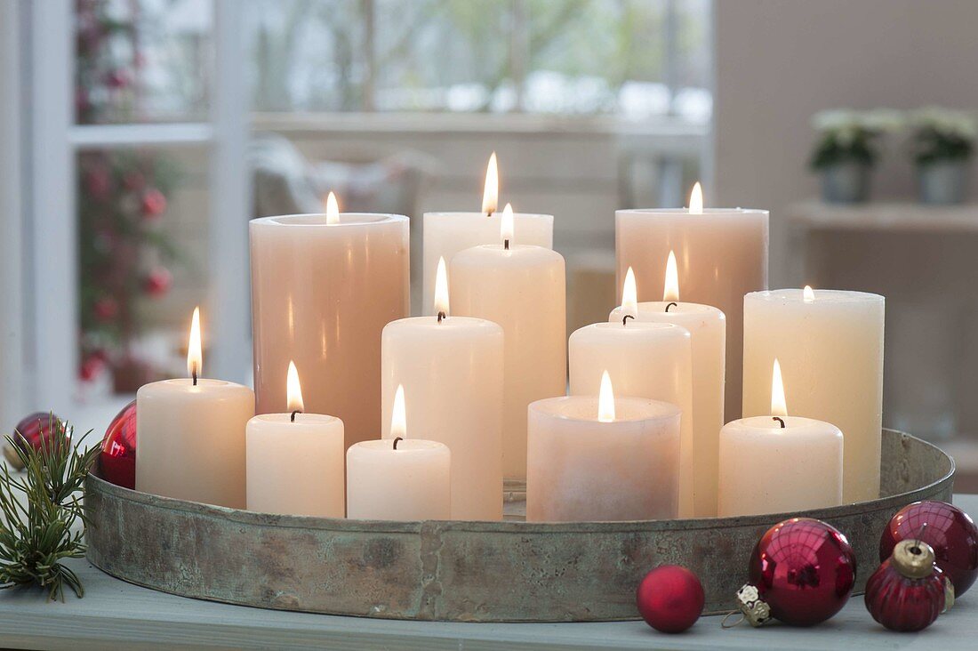 Metal tray with white candles, red tree balls next to it