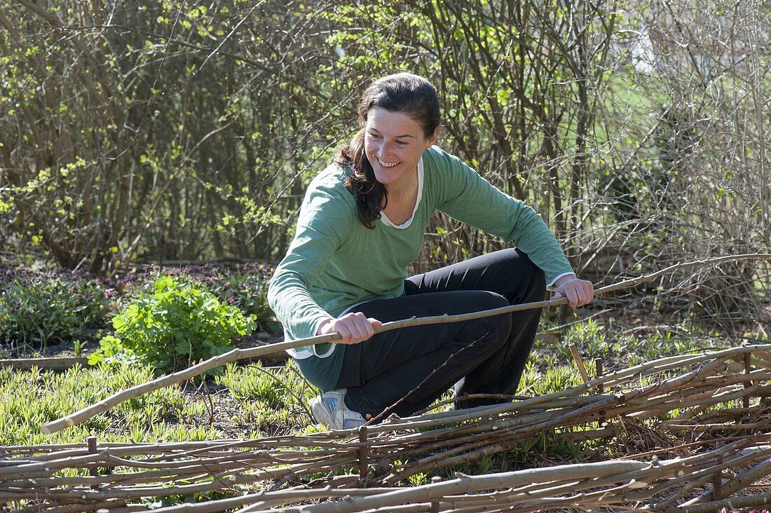 Woman braiding flower bed out of branches