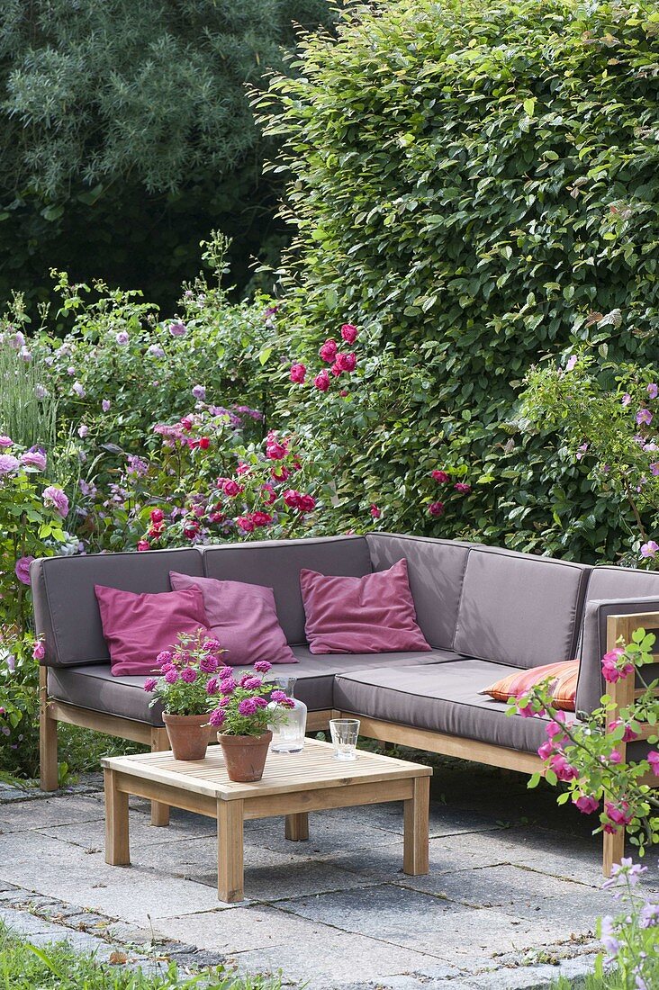 Lounge-Ecke auf kleiner Terrasse zwischen Rosen