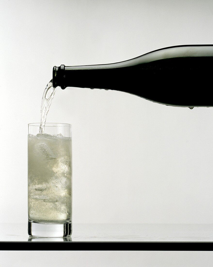 Champagner ins Longdrinkglas mit zerstoßenem Eis gießen
