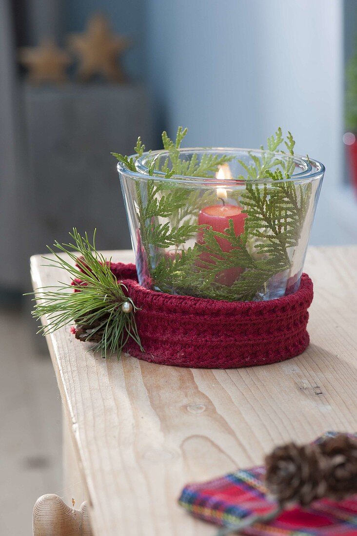 Glass with red candle as lantern, decorated with thuja