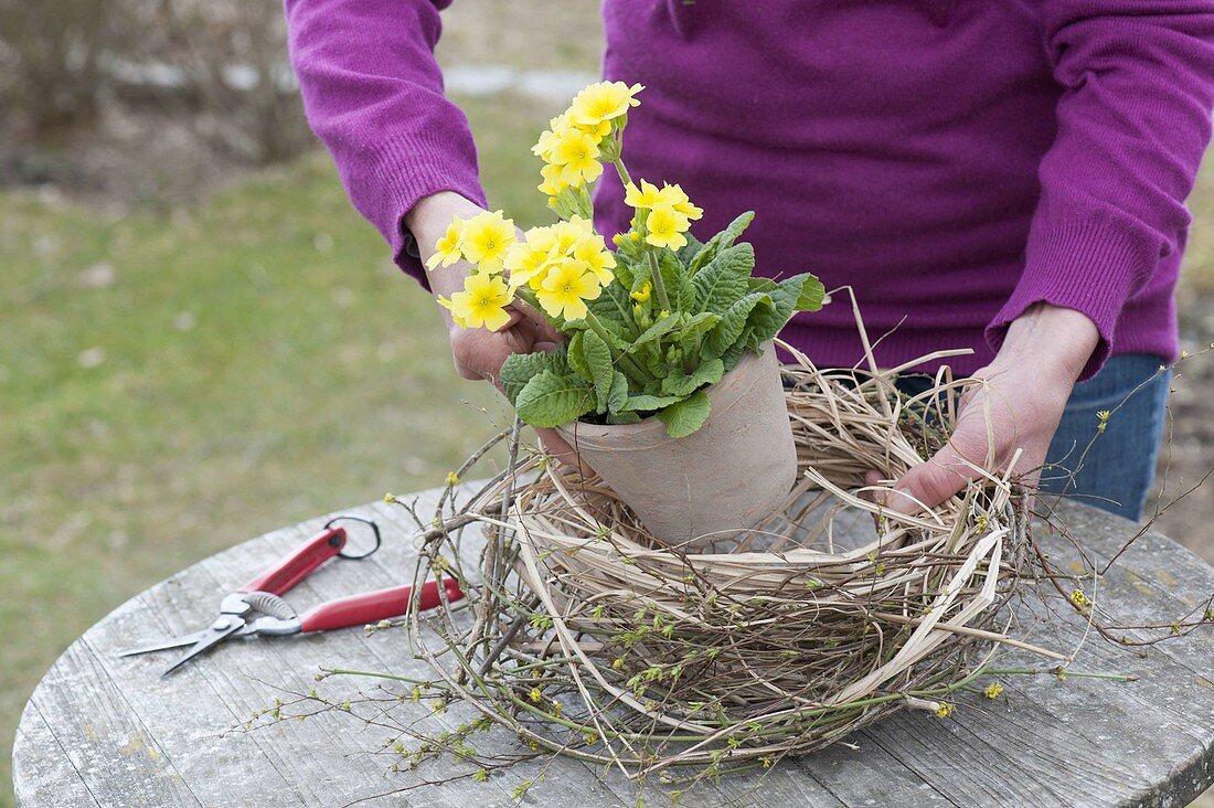 Easter table decoration with wreath of twigs, grasses and yellow primrose