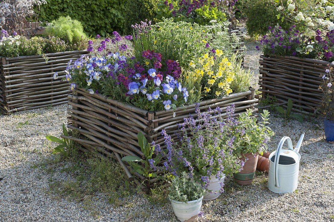 Gravel terrassse with raised beds made of hazelnut rods