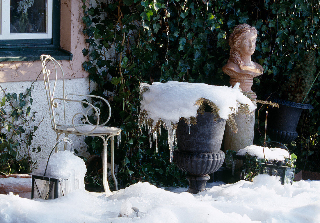 Vereiste, verschneite Terrasse mit Stuhl, Hedera (Efeu) an Hauswand, Frauenbüste auf Säule