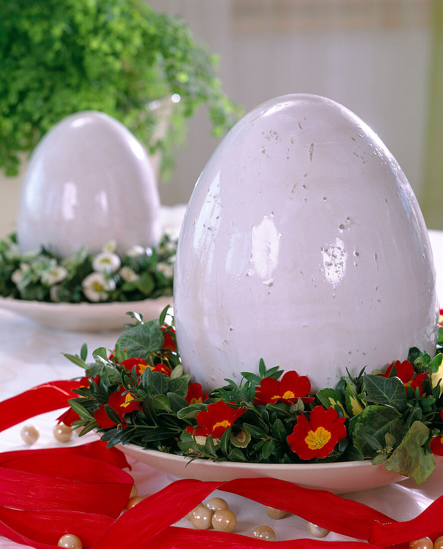 Ceramic egg with a wreath of primrose flowers, boxwood and ivy