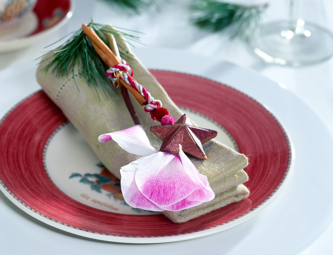 Christmas napkin decorated with cyclamen blossom, cinnamon stick, pine branch