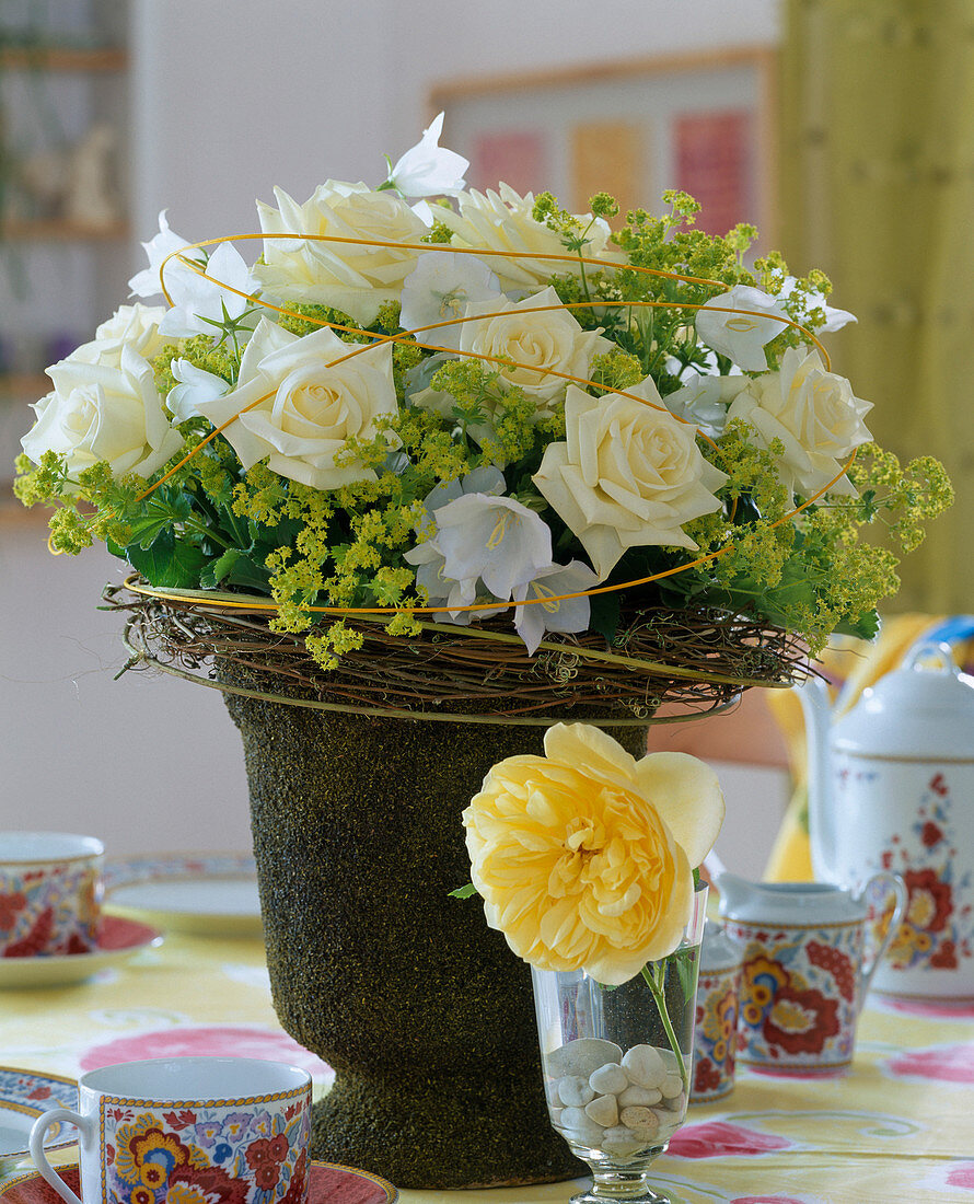 White roses and Alchemilla mollis (lady's mantle) in a moss vase