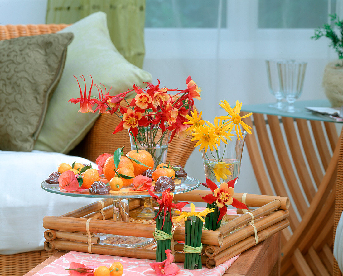 Table decoration with columbine, yellow daisy and citrus fruits