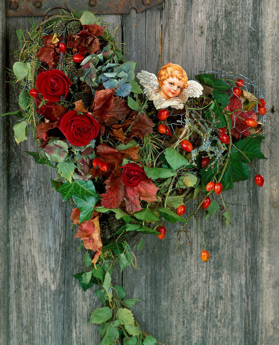Door arrangement: Heart made of wire mesh filled with leaves and decorated with rose petals