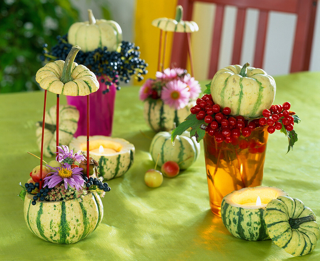 Table decoration with hollowed out ornamental pumpkins as tea light and vase, aster flowers
