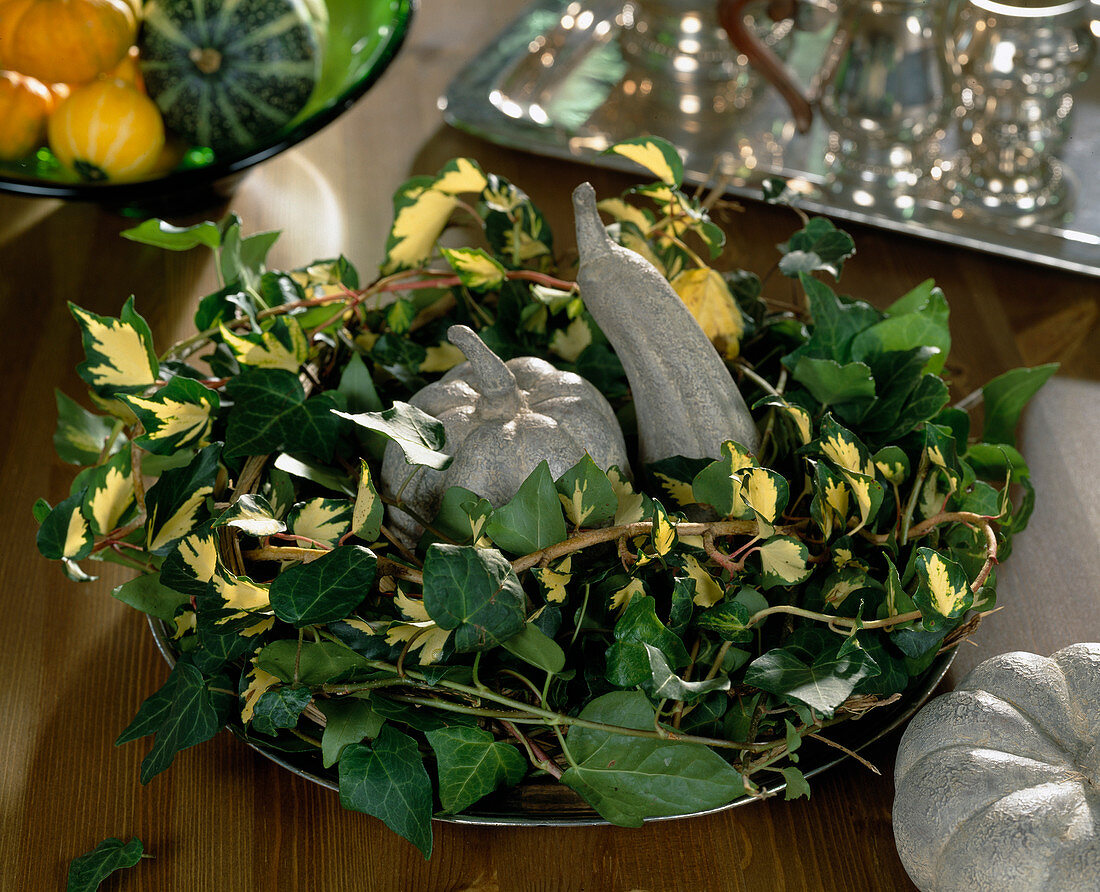 Autumn wreath made of Hedera helix (ivy), ornamental pumpkins made of cement