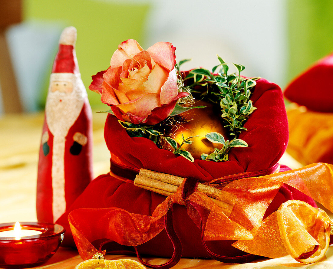 Velvet bag filled with pebbles and decorated with gold balls, box branches and rose blossom