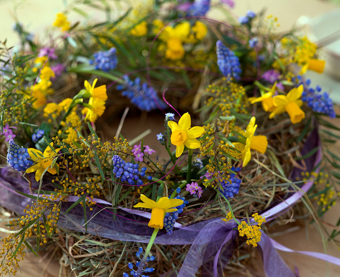 Wreath of hay with daffodils and grape hyacinths