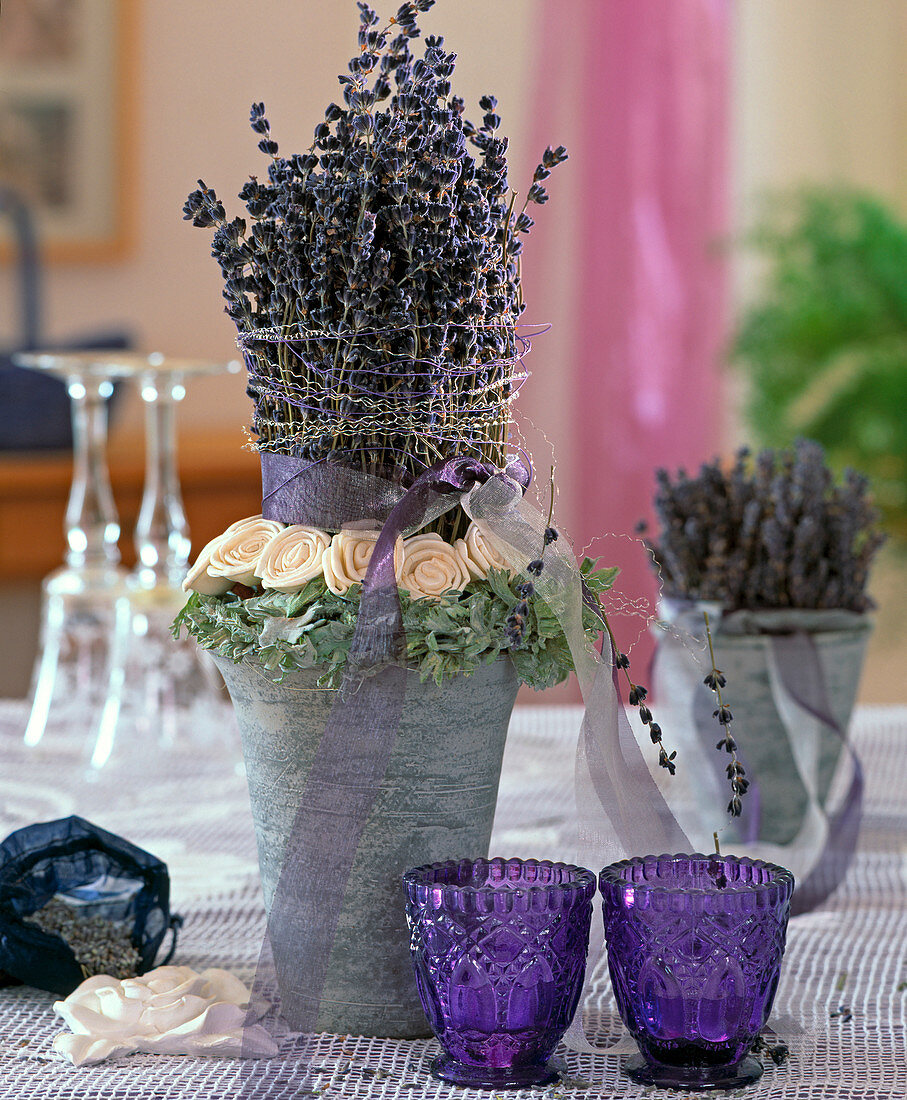 Getrockneter Lavendel als Säule gesteckt und mit weißen Seidenrosen und Silberdraht dekoriert