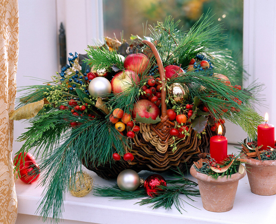 Basket with arrangement of branches, apples, balls and candles