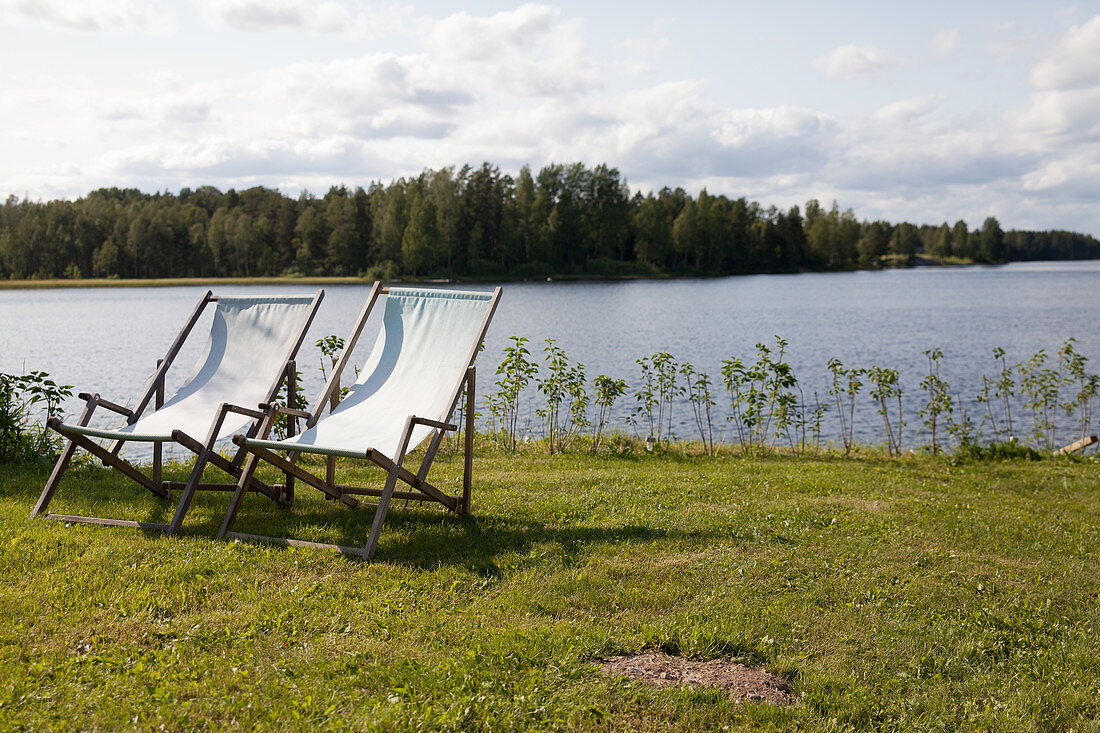 Zwei Liegestühle auf der Wiese am See