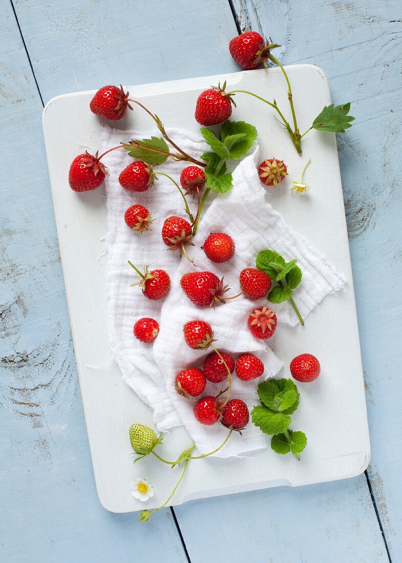 Erdbeeren mit Blättern auf Schneidebrett