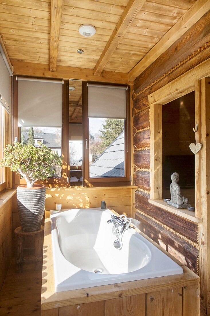 Holzverkleidete weiße Badewanne in rustikaler Datcha mit Fensterausschnitt in Holzwand